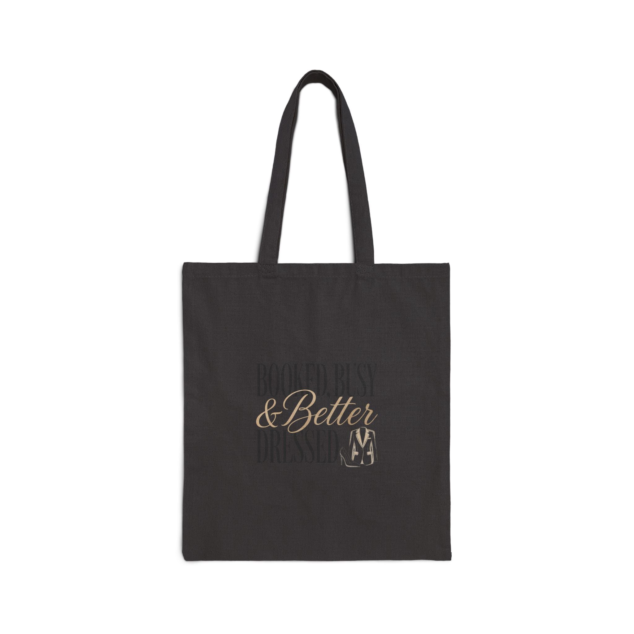 A black canvas tote bag featuring the text Booked Busy and Better Dressed in gold and grey.