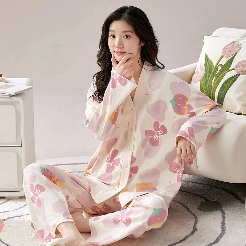 A woman wears a long-sleeved, V-neck pajama set featuring a pink and white strawberry print.