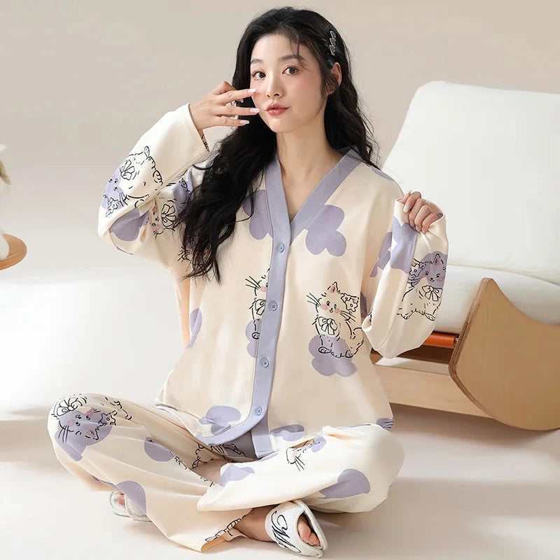 A woman wears a long-sleeved, V-neck pajama set featuring a cream background with purple cloud and cat prints.