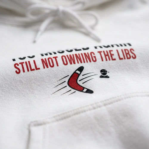 A white hooded sweatshirt featuring the text Still Not Owning The Libs and a red boomerang graphic.