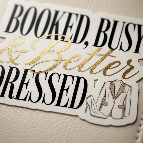 A glossy sticker featuring the text Booked Busy and Better Dressed with a blazer and heel icon.