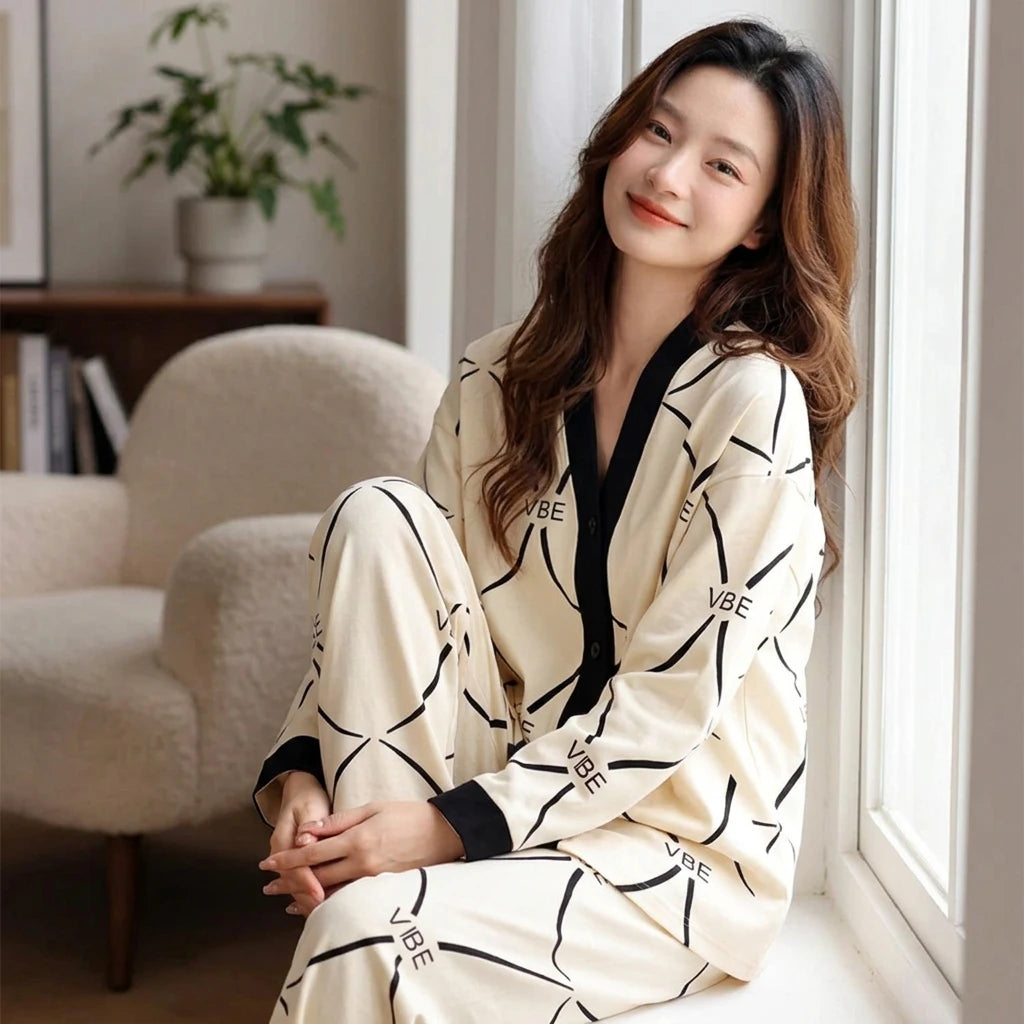 A woman wears a cream-colored long-sleeved pajama set with a black geometric print and V-neck.