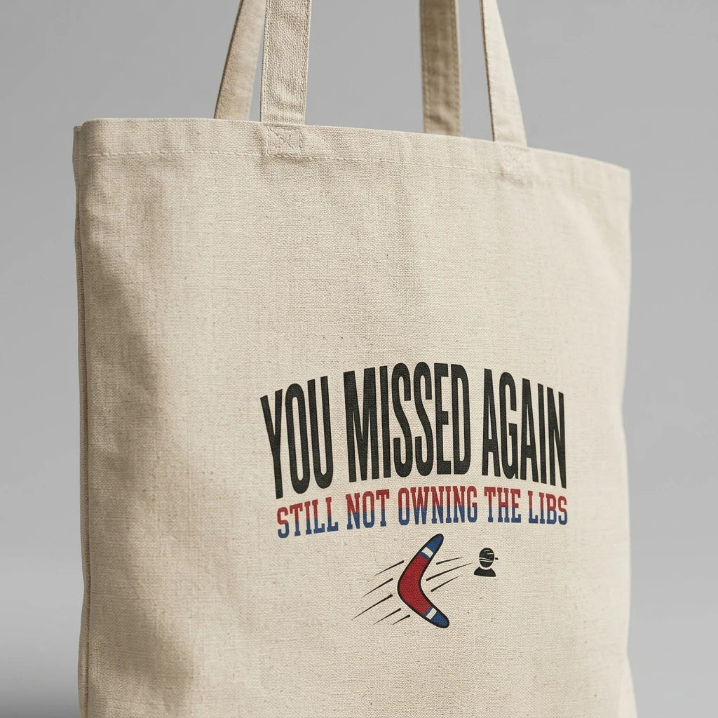 A natural canvas tote bag featuring the text You Missed Again and a red, white, and blue boomerang.