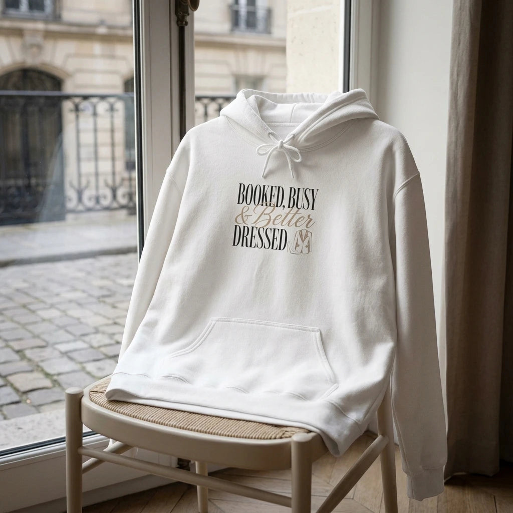 A white hooded sweatshirt with the text Booked, Busy and Better Dressed printed on the chest.